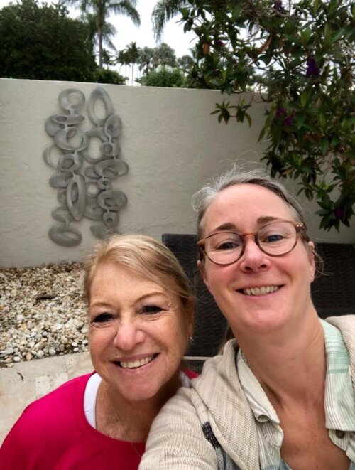 Cherie and her latest client in front of freeform olive wall sculpture