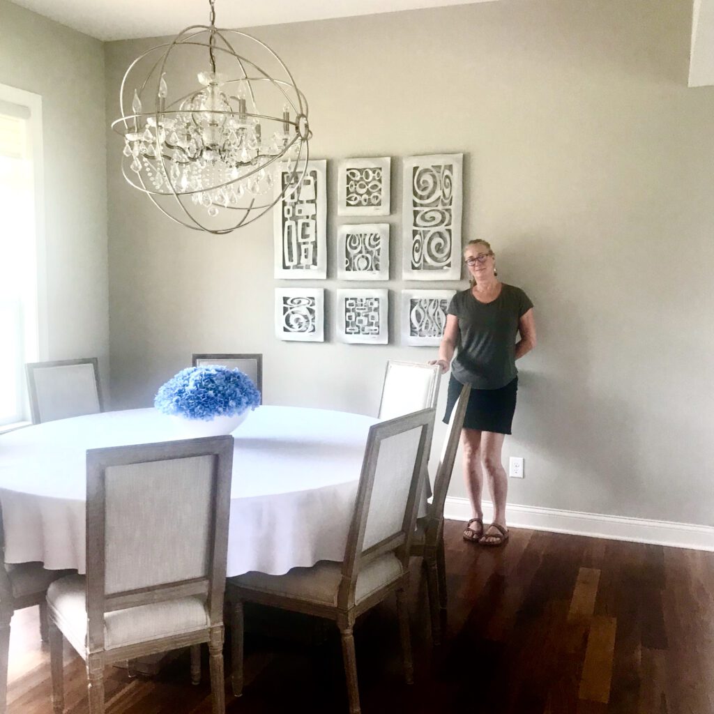Cherie standing next to a group of tiles in a dining room