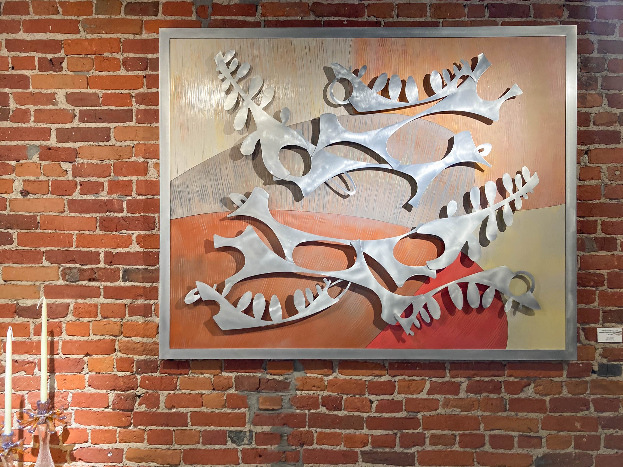 Abstract shapes evoking compound leaves, delicate curves, and woody colors make up this large wall sculpture hanging prominently in the gallery.
